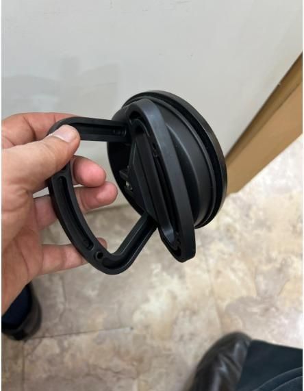 Black carabiner held by a hand against a neutral background