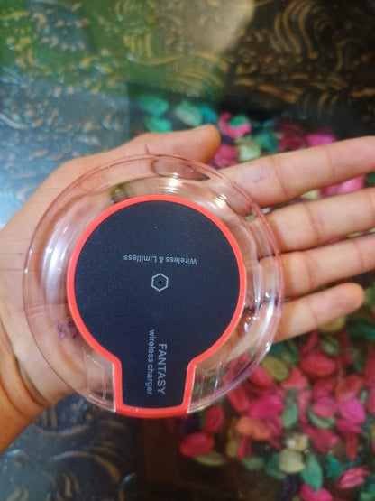 Hand holding a wireless charger with 'Fantasy' branding against a colorful background