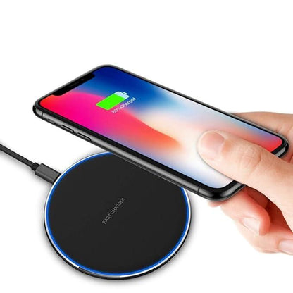 Hand holding a smartphone above a wireless charging pad with a white background
