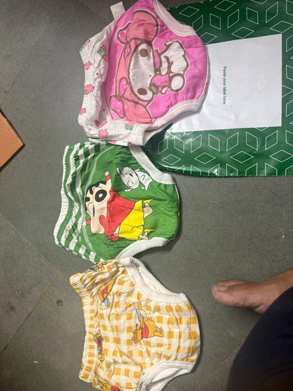 Three children's underwear with cartoon designs on a gray floor.