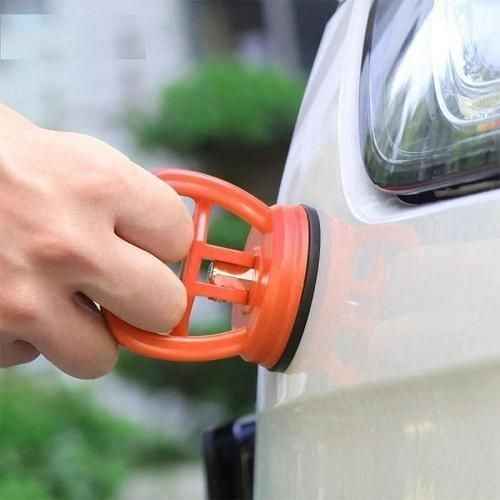 Hand using an orange car air freshener clip on a car's rearview mirror.