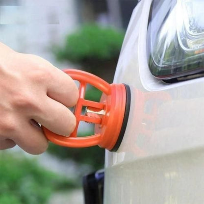 Hand using an orange car air freshener clip on a car's rearview mirror.