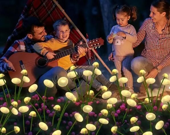 Family playing guitar in a field of glowing flowers at night