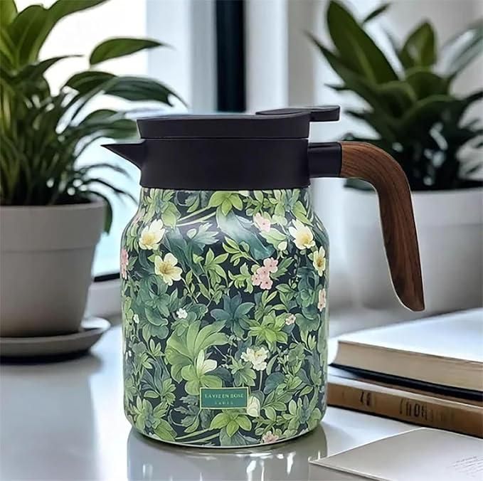 Floral-patterned thermos with wooden handle on a surface with plants and books in the background