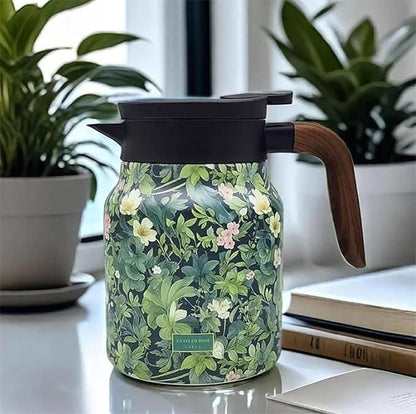 Floral-patterned thermos with wooden handle on a surface with plants and books in the background