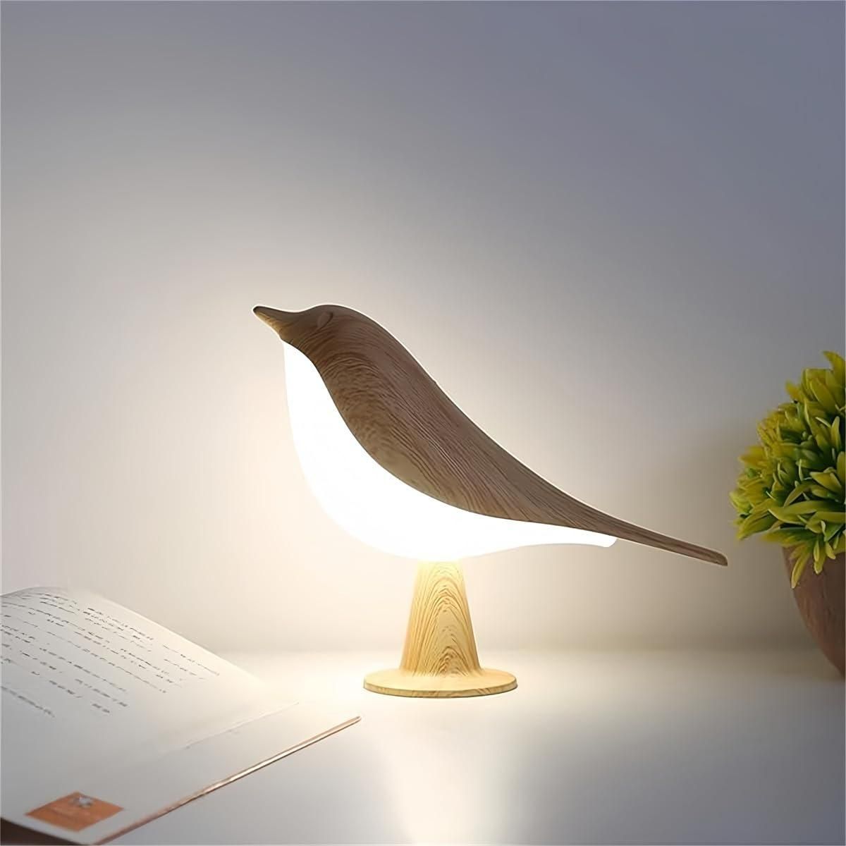 Bird-shaped lamp on a desk with a plant and paper in the background